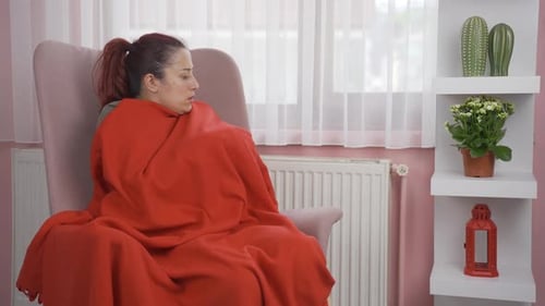 The woman is cold and is touching the heater.