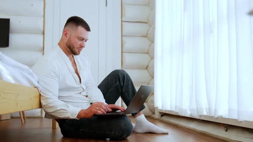 Man Working on Laptop Sitting on Floor