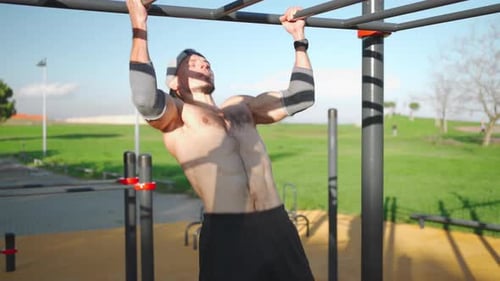 Muscular Athlete Doing Pull Ups on Horizontal Bar at Outdoors Park