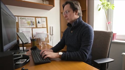 Man working with a computer in an office. Focusing on work and typing on the keyboard.