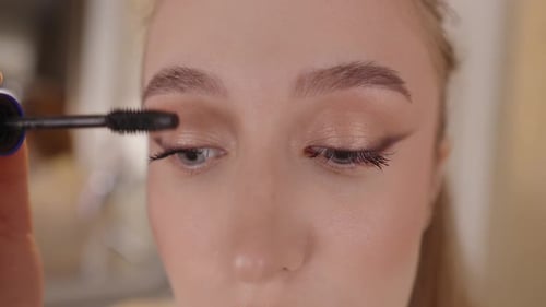 Closeup Woman Applying Makeup Applying Black Mascara with a Brush to Upper Lashes Close Up on the