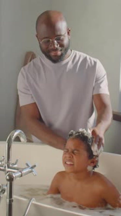 Man Washing Child's Hair in Bathtub with Soap