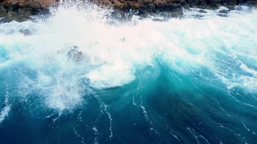 Sea Waves Washes the Rocky Shore Above Aerial Shot Flying Over Coastline Cliffside with Blue Pure