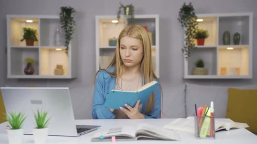 Female student working between paper and laptop.