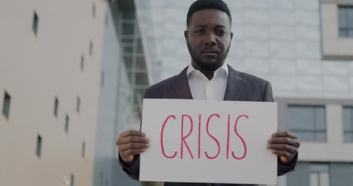 Slow Motion Portrait of Troubled African American Man Holding Crisis Banner Standing Outdoors in