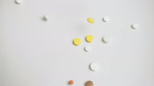 Multicolored Pills Falling on White Table A Vivid Medication Scene