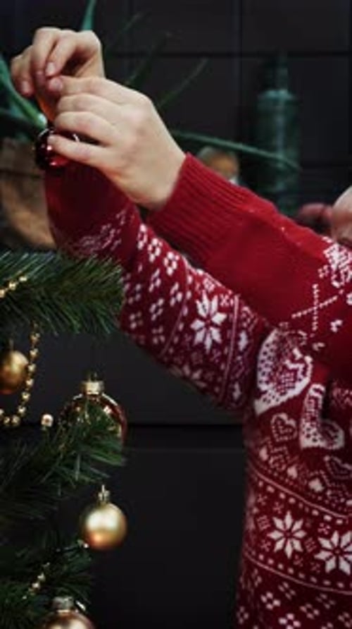 Woman Decorating Christmas Tree with Ornaments at Home