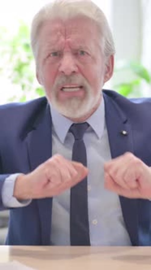 Angry Senior Businessman Gesturing Aggressively at the Camera