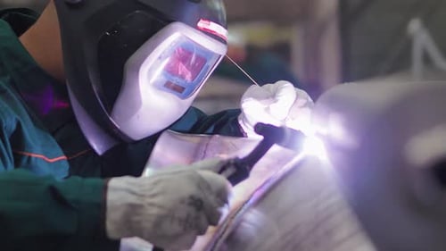 Welder, using VIG, TIG, MIG MAG method to welding stainless steel parts, close up. The welder uses a