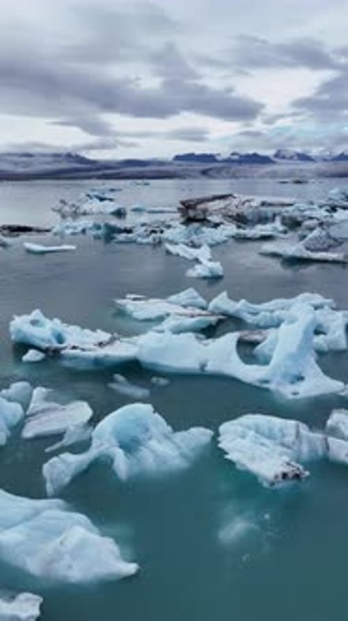 Flying over the Jökulsárlón lagoon, beautiful aqua waters with stunning icebergs in Iceland.