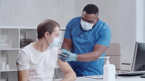Adult Man Receives Vaccine from Medical Professional
