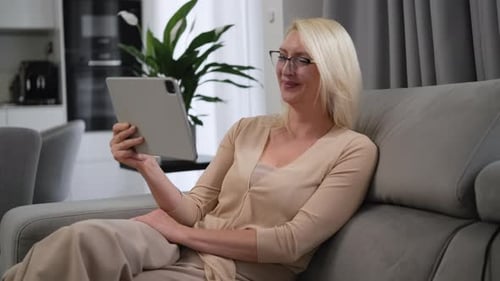 Mature Blonde Woman Relaxing Indoors with Tablet