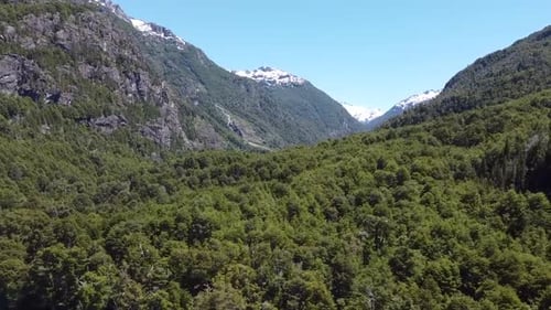 Río azul con montañas nevadas y bosque verde