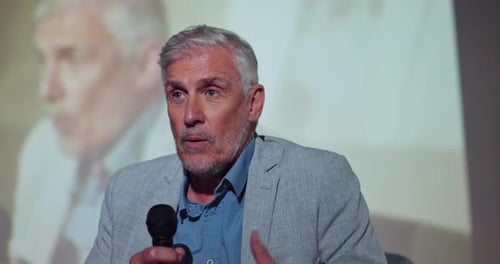 Man Speaking at a Corporate Event Holding Microphone