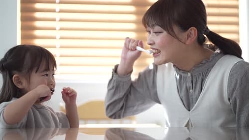 Woman and Child Brushing Teeth Together at Home