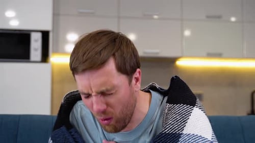 Sick Man Holding His Chest in Pain While Coughing in the Living Room