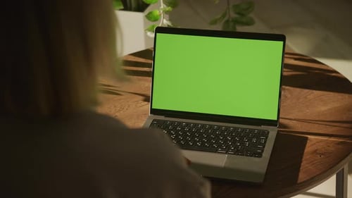 Handheld Shot of an Unrecognisable Caucasian Woman Watching a Laptop Computer with Green Screen