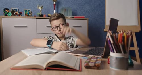 Focused Child Studying At Desk With Laptop