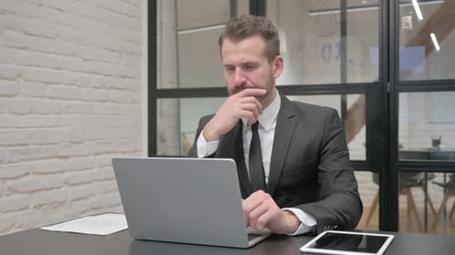 Pensive Middle Aged Businessman Working on Laptop