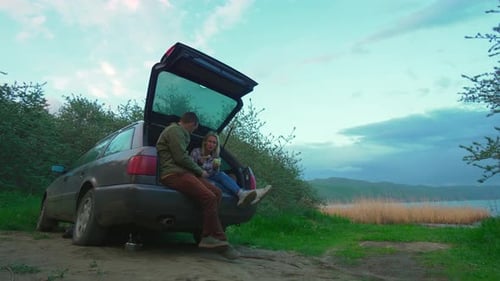 Couple Relaxing at Car Hatchback Overlooking Scenic Lake