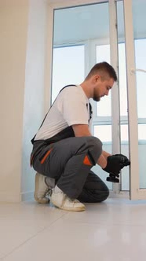 Handyman Using Drill Installing New Window in Apartment