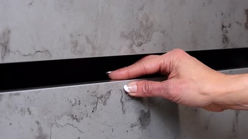 Woman with painted fingernails opens and closes cabinet drawer