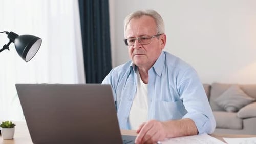 Mature Adult Working on Laptop at Home Desk