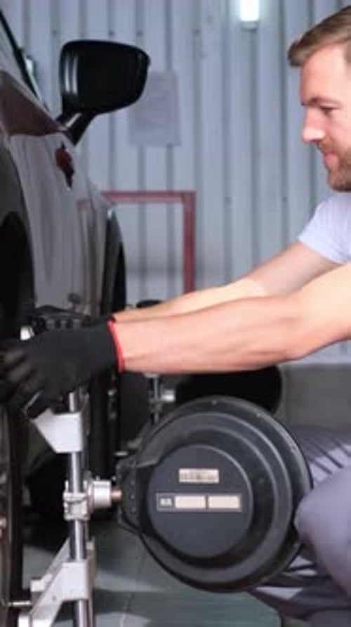 A Man is Fixing an Auto Part on a Vehicle in a Garage