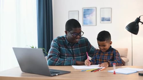 Schreiben lernen. Vater mit seinem Sohn ist zusammen drinnen im Hausraum
