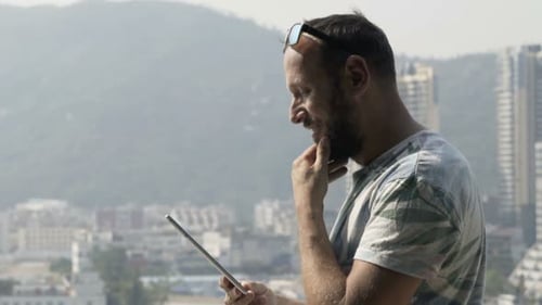 Man Using Tablet Computer Standing On Terrace In City