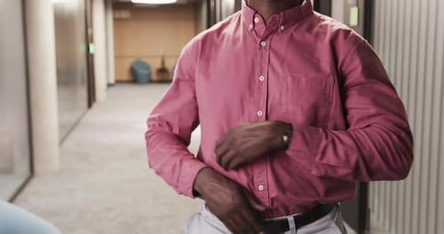 Confident businessman standing with arms crossed in modern office hallway