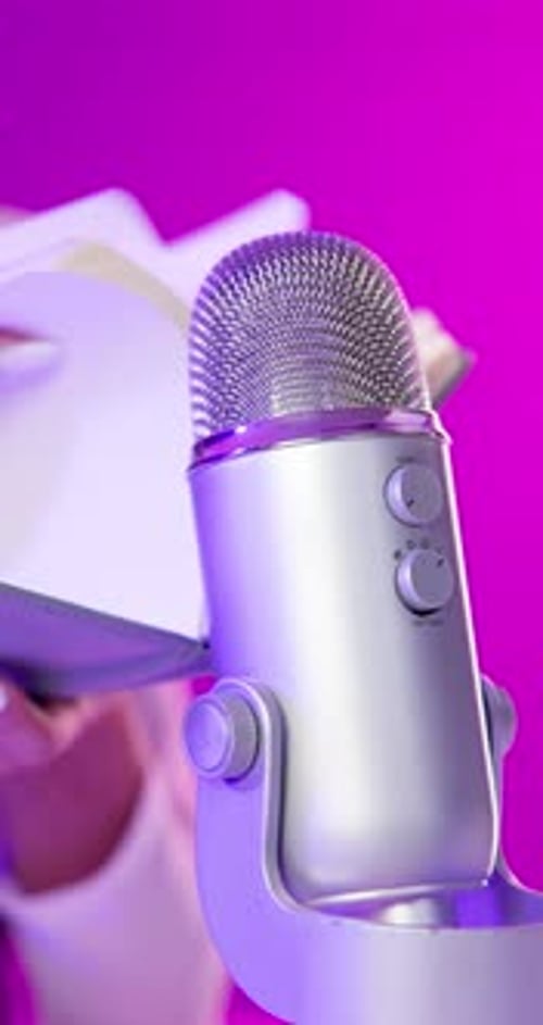 Microphone, book and hands of person on pink background for audio or sound therapy and podcast