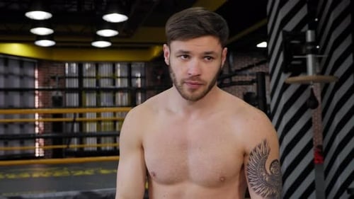 Young Man with Black Bandages on His Hands Practices Punches in the Boxing Ring