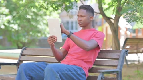 Young Adult Using Tablet on Park Bench