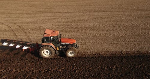 Tractor Plowing Field from Above in Rural Farmland
