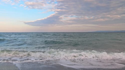 Black Sea and Beach Nearby Against a Sky with Clouds and a Dawn Sun