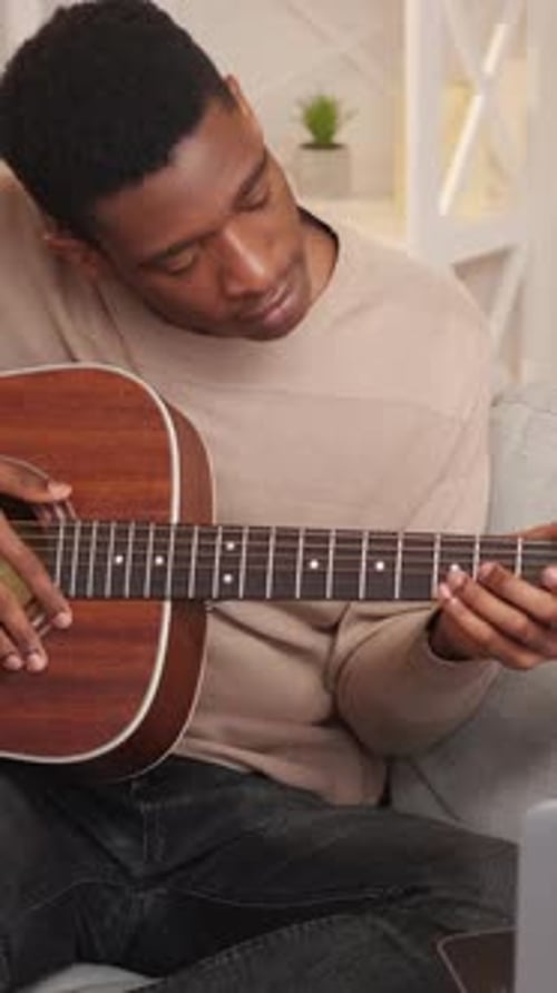 Young Adult Playing Acoustic Guitar While Seated