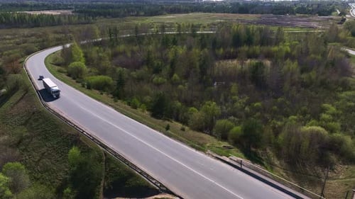 Aerial view Trucks and light vehicles drive on a country road on a sunny spring day.
