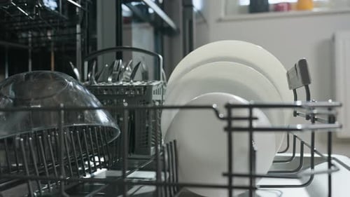 Woman Loading Plates in Modern Dishwasher