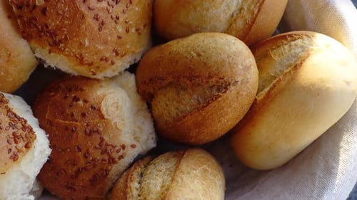 Freshly Baked Bread Rolls in a Woven Basket on Rustic Surface