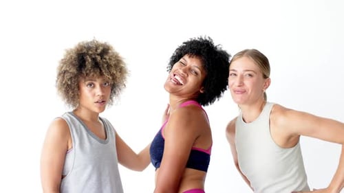 Three women are posing playfully against a white background