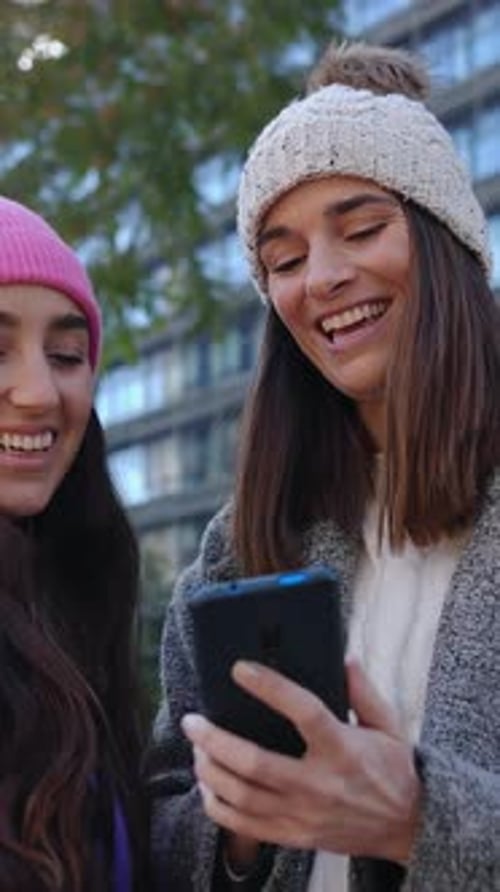 Young Women Interact with Smartphone in City