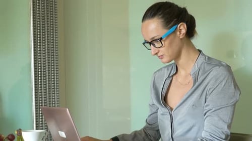 Young Businesswoman Working on Laptop Sitting by Table in Office 30s
