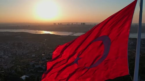Waving Flag Over City at Sunrise