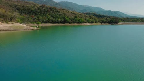 Aerial drone flying over a blue water lake with mountains landscape