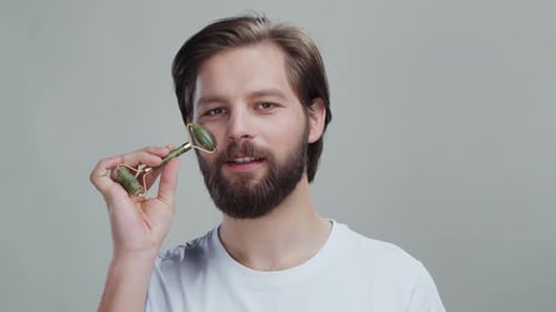 Man Using a Jade Facial Roller Tool