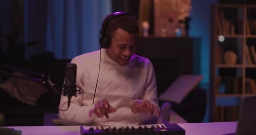 Young man plays keyboard at home recording music