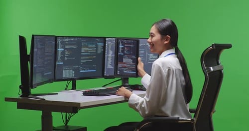 Entwicklerin arbeitet mit einem Tablet, während sie im Green Screen Studio Code mit mehreren Bildschirmen schreibt
