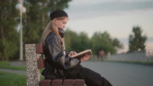 Youth Reads Peacefully Teen Engrossed in Book Outdoors Young Person Relaxing with Literature in Park