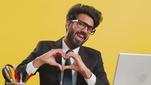 Cheerful Young Adult Makes Heart Shape at Desk